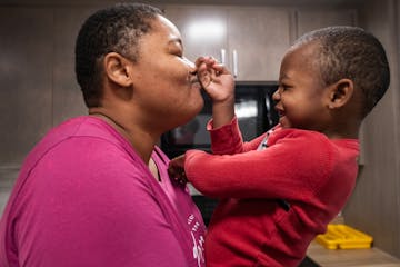 Frankey Smith nuzzles her son Robert in the kitchen of their new home in Hopkins.