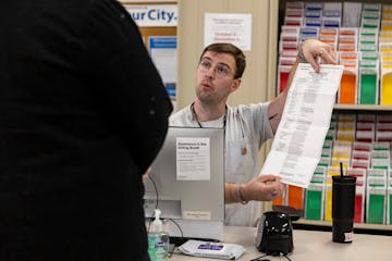 Seasonal Election Support Specialist Zach Becka helps a voter by displaying an empty ballot during early voting at Minneapolis Elections and Voter Ser